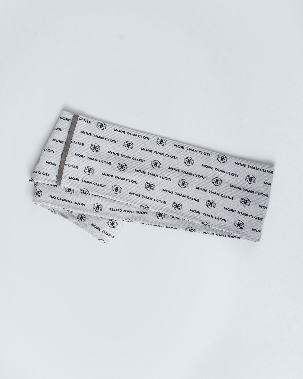The light grey printed snood laid flat and folded, seen from above on a white surface