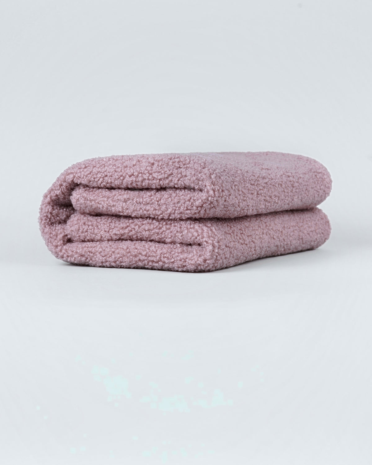 Powder pink bouclé small dog blanket folded neatly on a light background