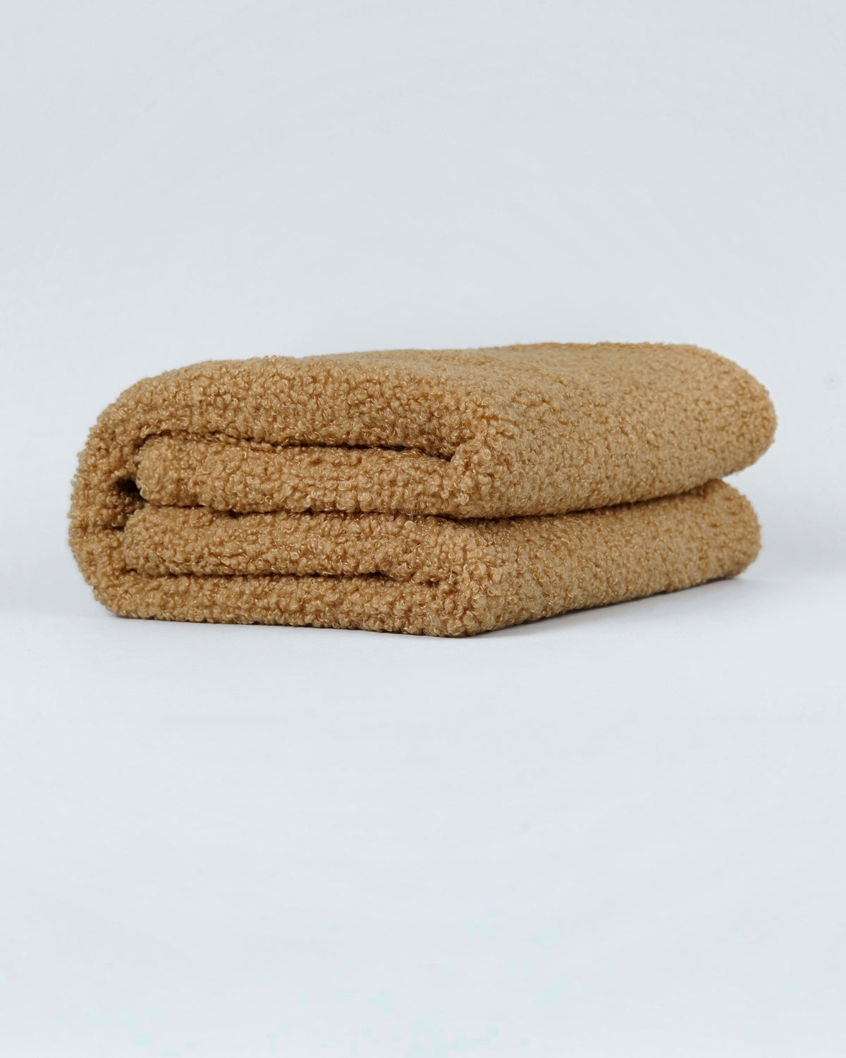 Camel bouclé dog blanket folded neatly on a light background