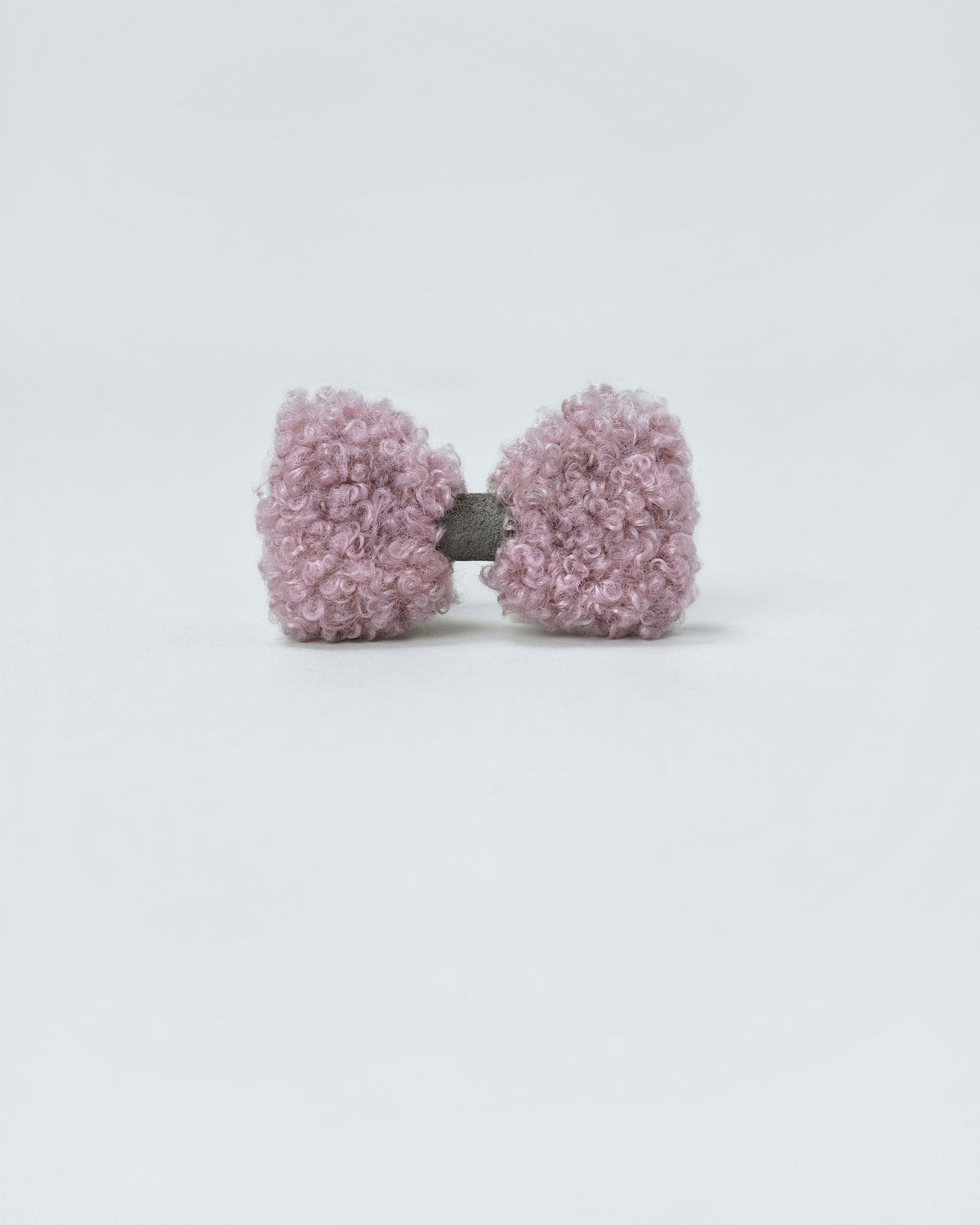Powder pink bouclé bow with a grey faux-suede centre on a light background