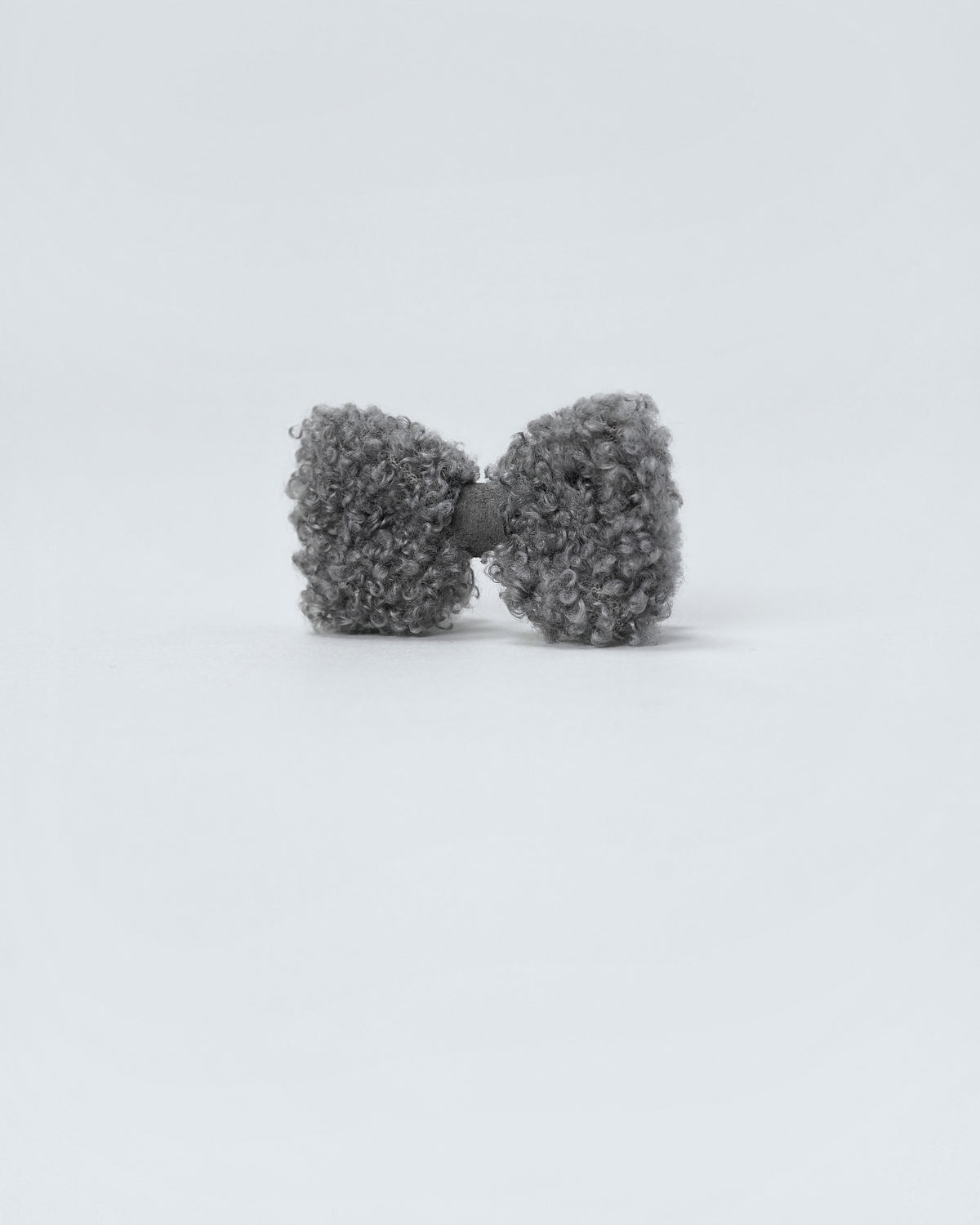 Grey bouclé dog hair bow seen at a slight angle, showing its soft teddy texture