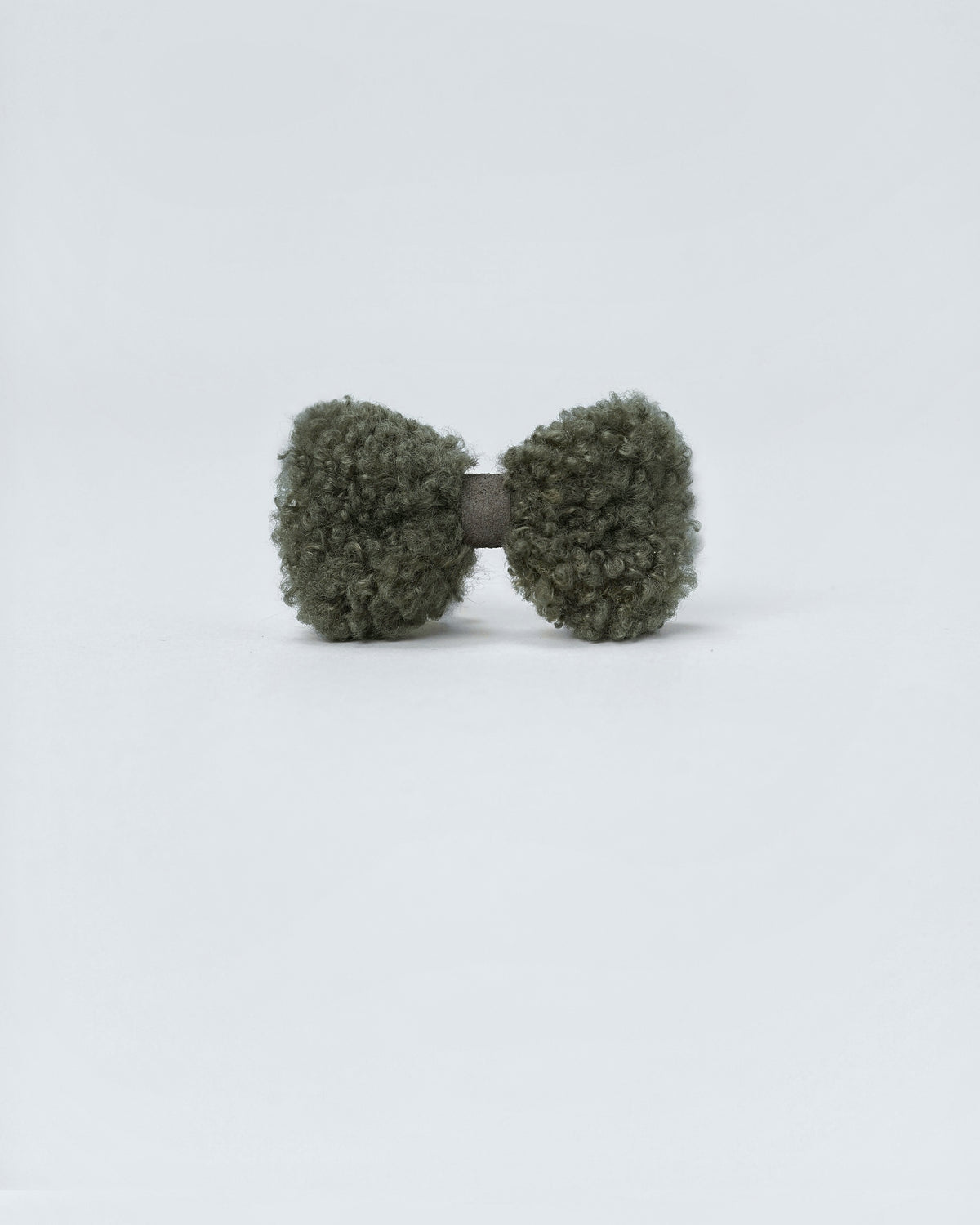 Front view of a forest green bouclé bow with a faux-suede centre