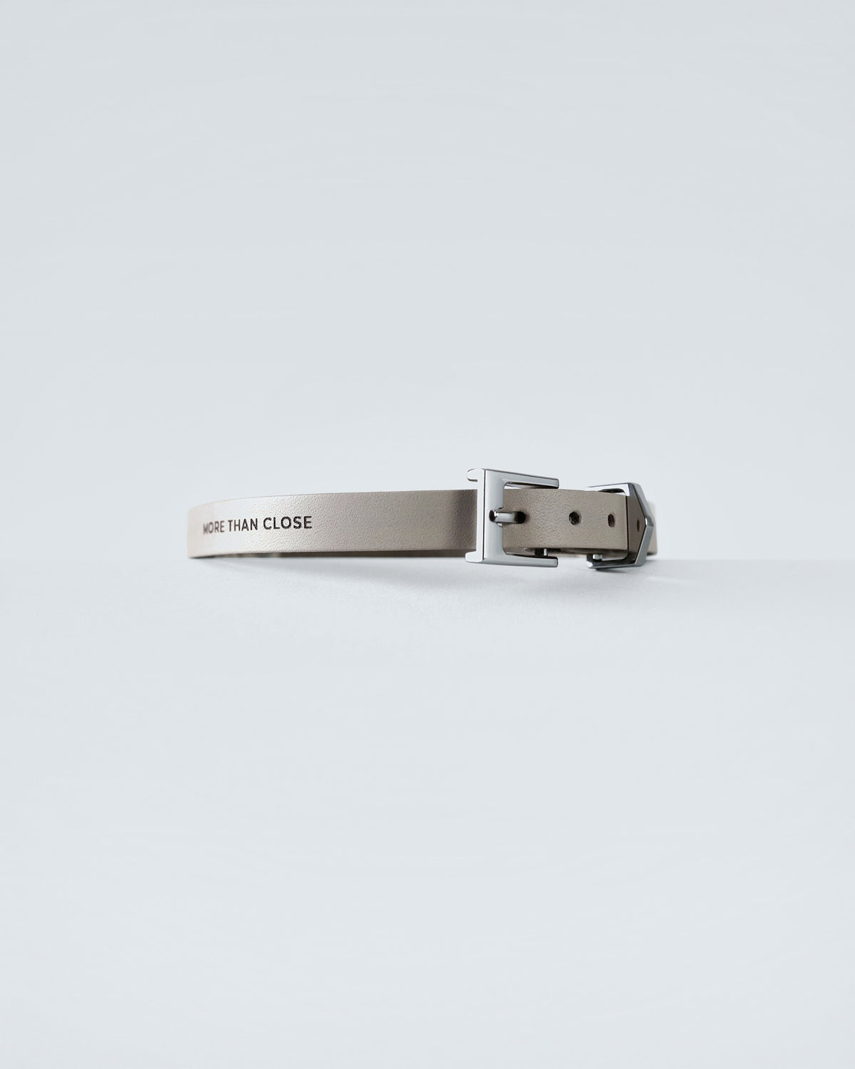 The greige collar shown at an angle, its buckle and punched holes catching the light