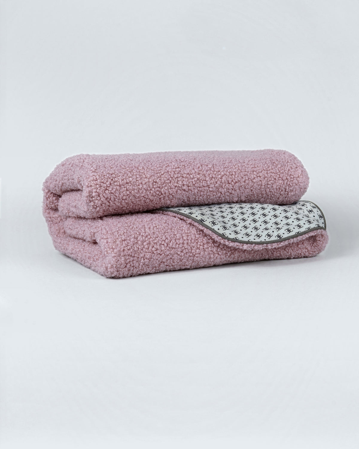 Powder pink bouclé small dog blanket folded to show its patterned lining