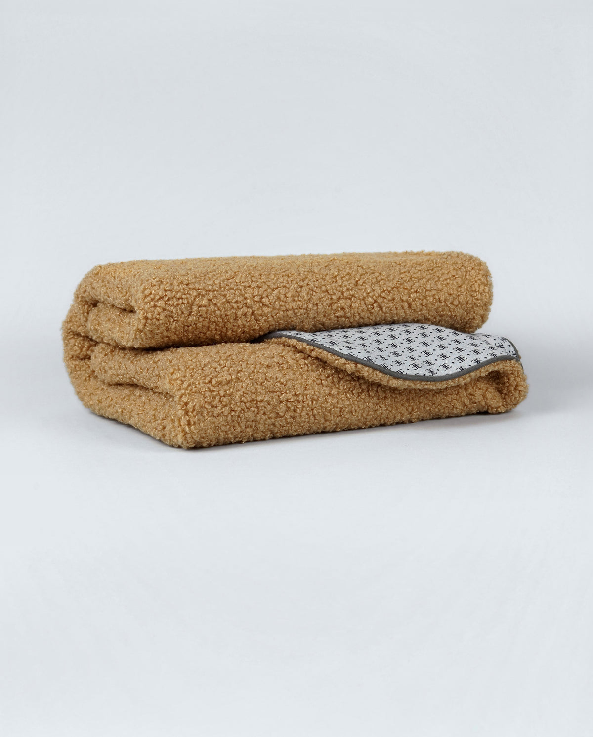 Camel bouclé blanket for dogs folded to show its patterned lining