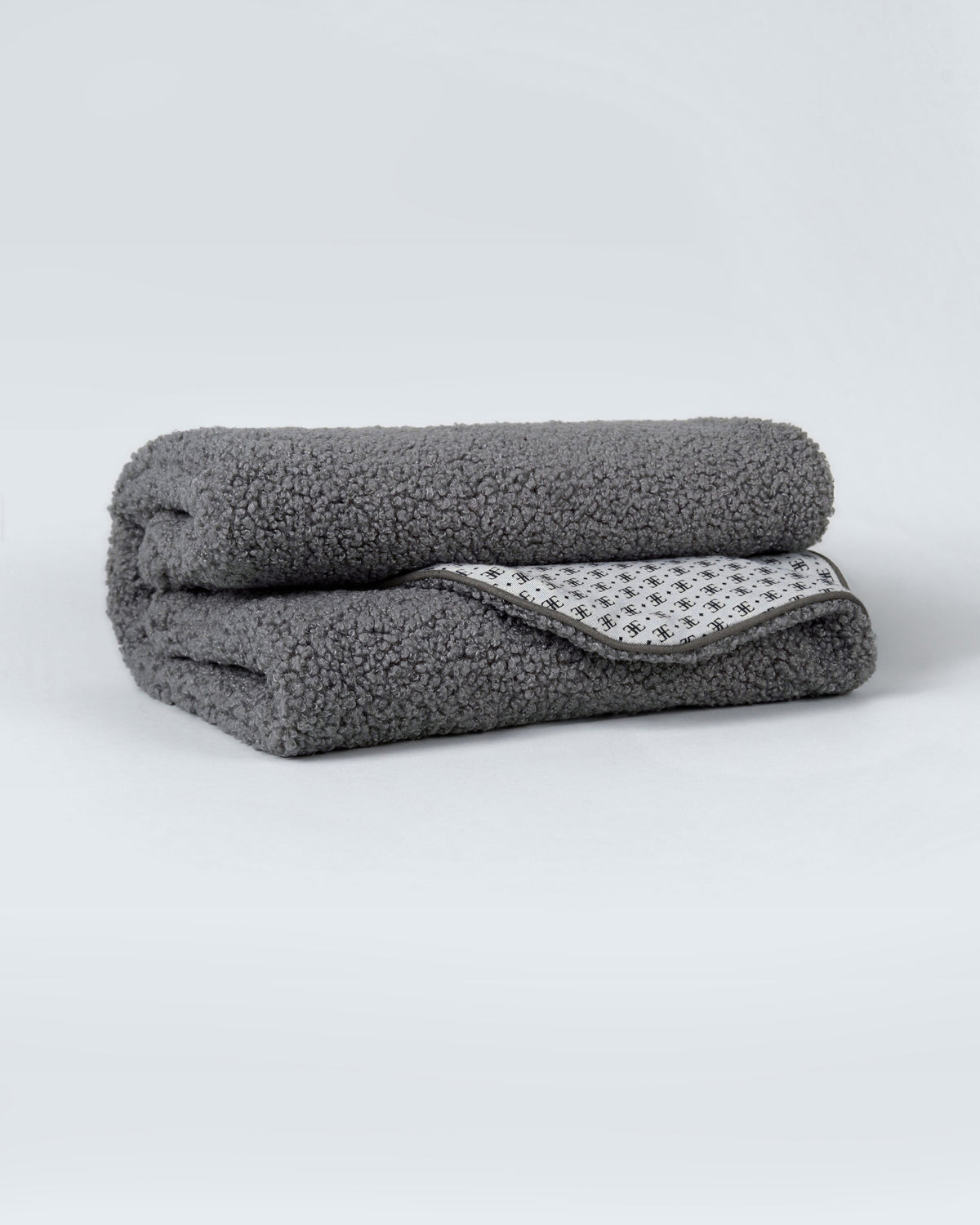 Grey bouclé dog blanket folded to show its patterned lining