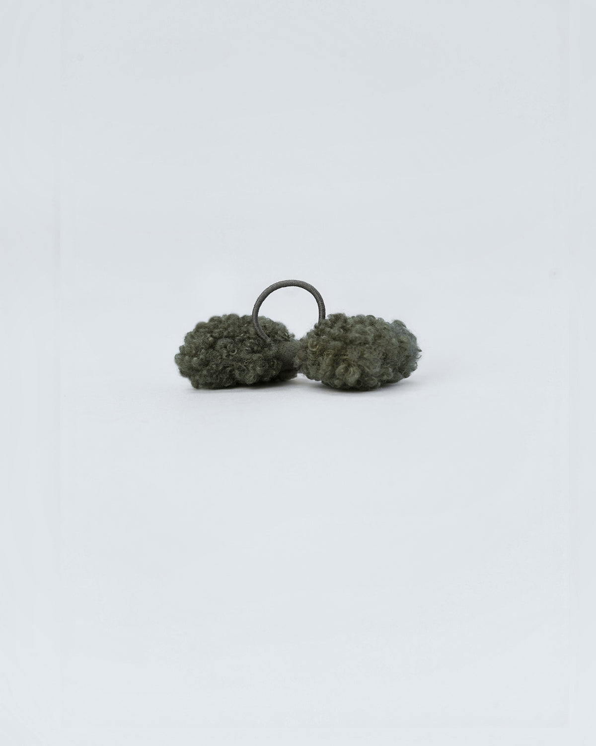 Back of a forest green bouclé dog hair bow showing its elastic loop
