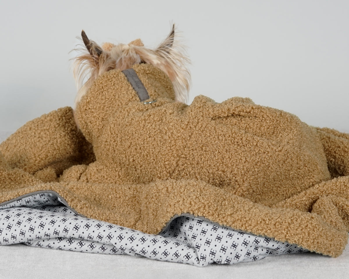 Close-up of a camel bouclé dog dress showing the back pleat, suede tab and patterned lining